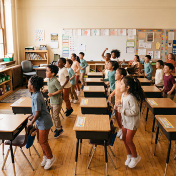 Elementary students playing phonemic awareness games with movement in a bright classroom